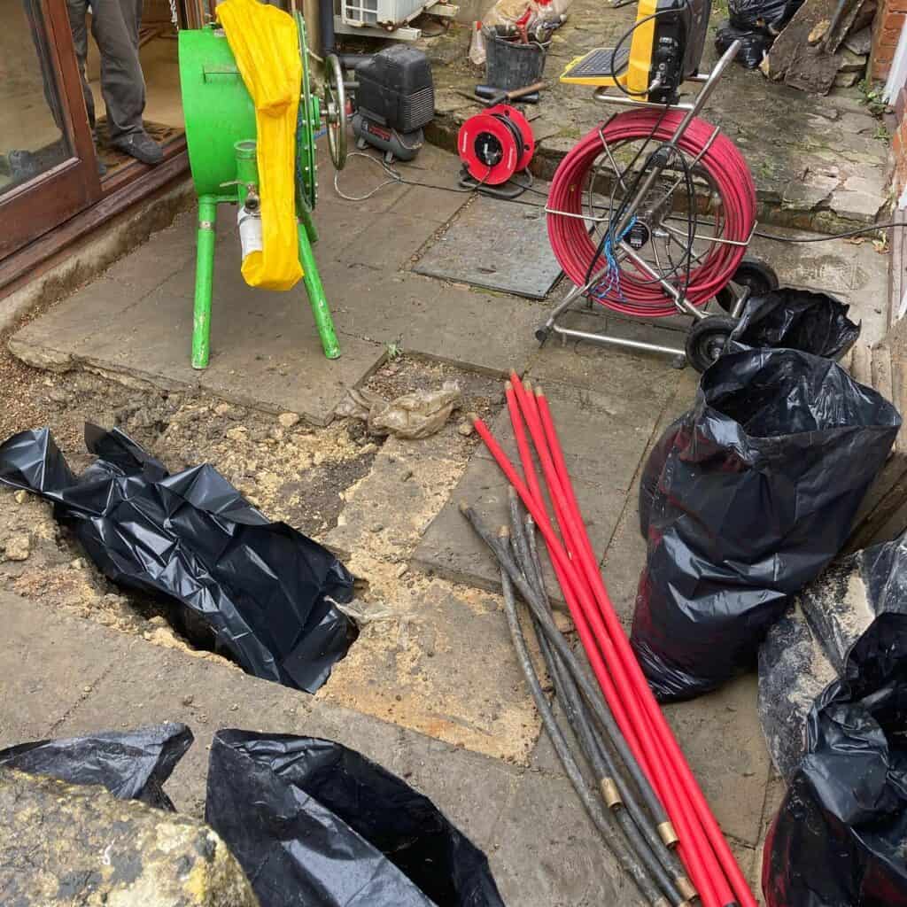 Drainage system installation in progress on a patio, with pipes and excavation work at site.